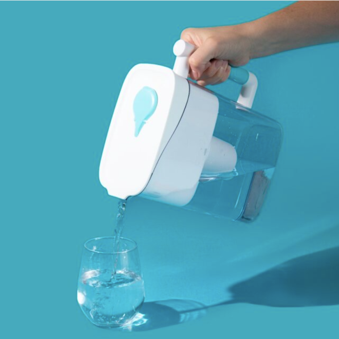 Hand pouring water from the Phox Wave water filter jug into glass