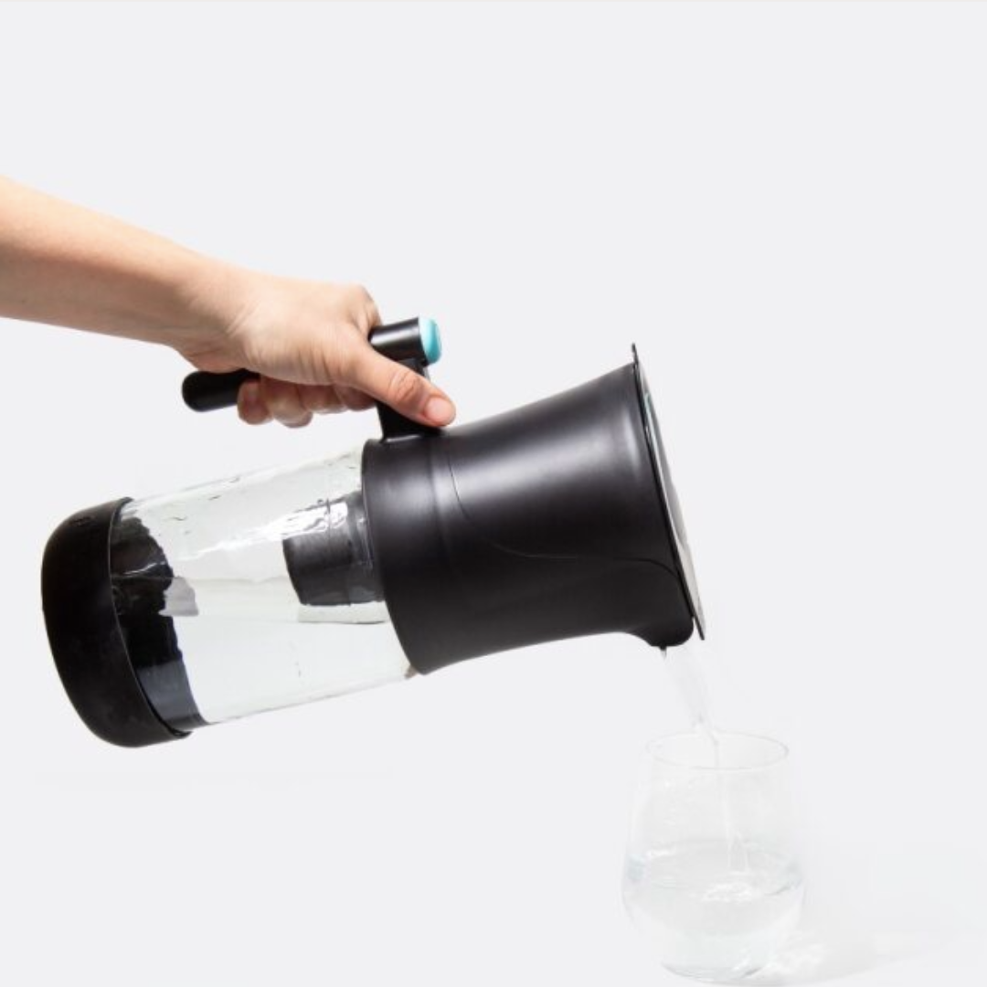Hand pouring water from Phox V2 water filter jug into glass